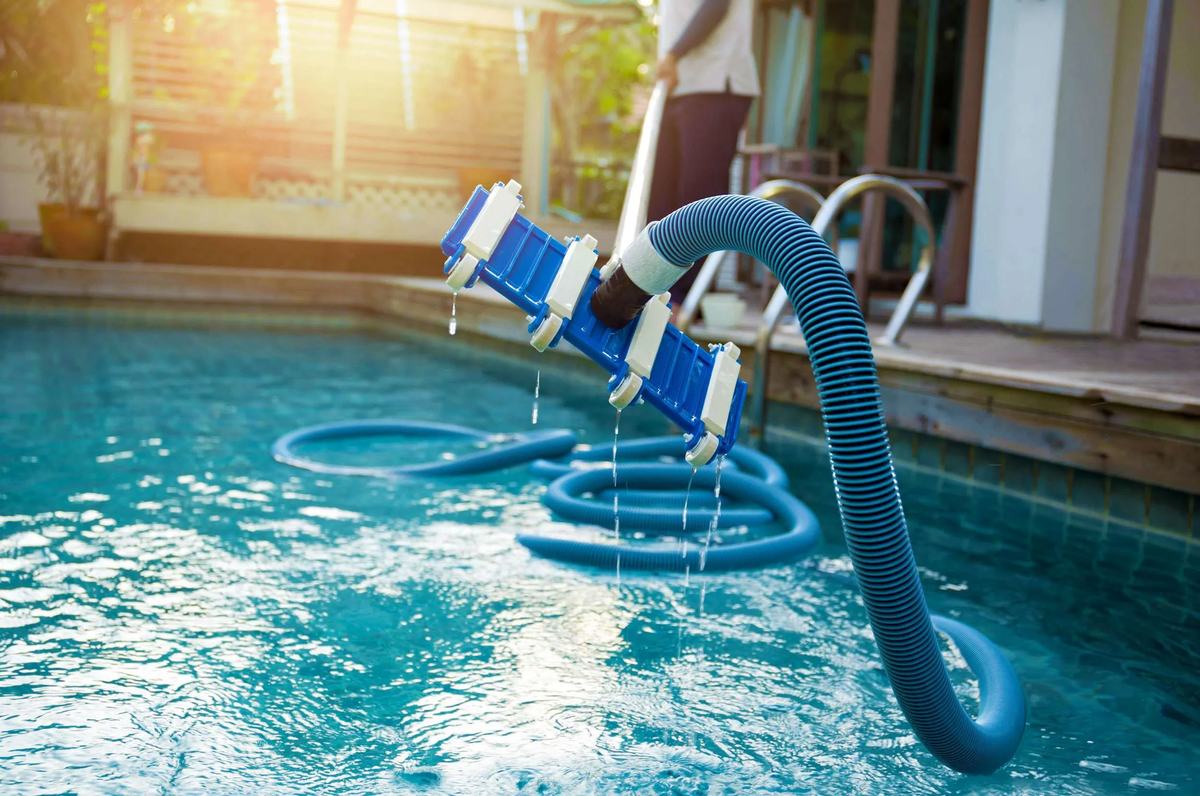 Manual pool vacuum head and hose beside a Peoria pool